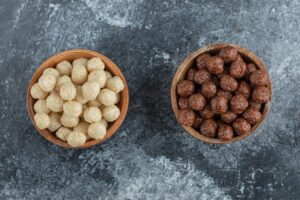 Wooden bowls with sweet corn balls on gray.